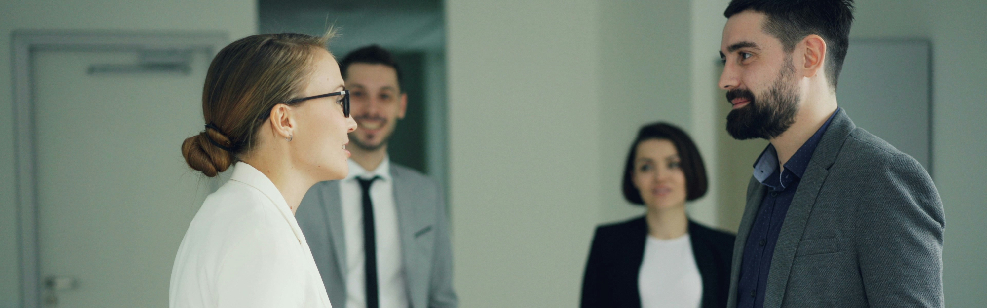 Two professionals talking with others in the background.