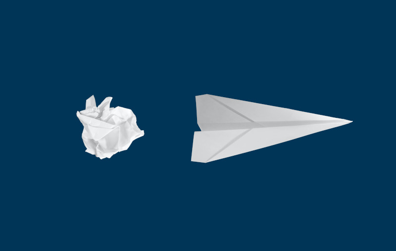 A white paper aeroplane on a blue background.