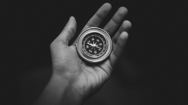 Hand holding a compass.